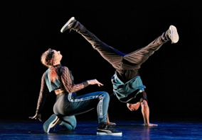 Ephrat Asherie dances onstage with one dancer doing a headstand and another dancer kneeling.