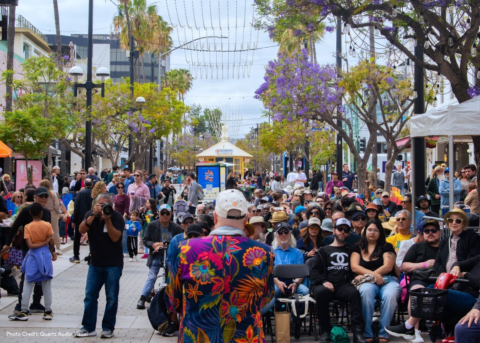 A packed crowd fills Third Street Promenade lined with trees and string lights.