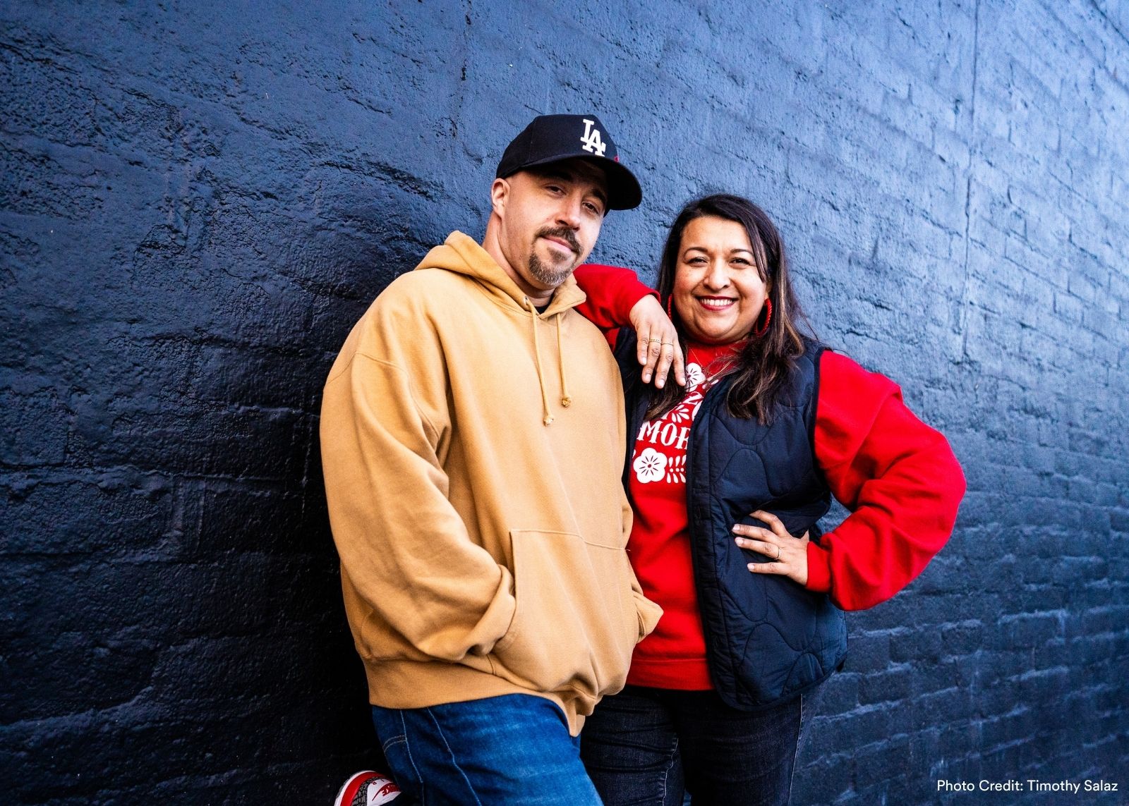  Versa-Style Dance founders Leigh Foaad and Jackie Lopez lean against a dark brick wall, smiling casually at the camera. Photo: Timothy Salaz.